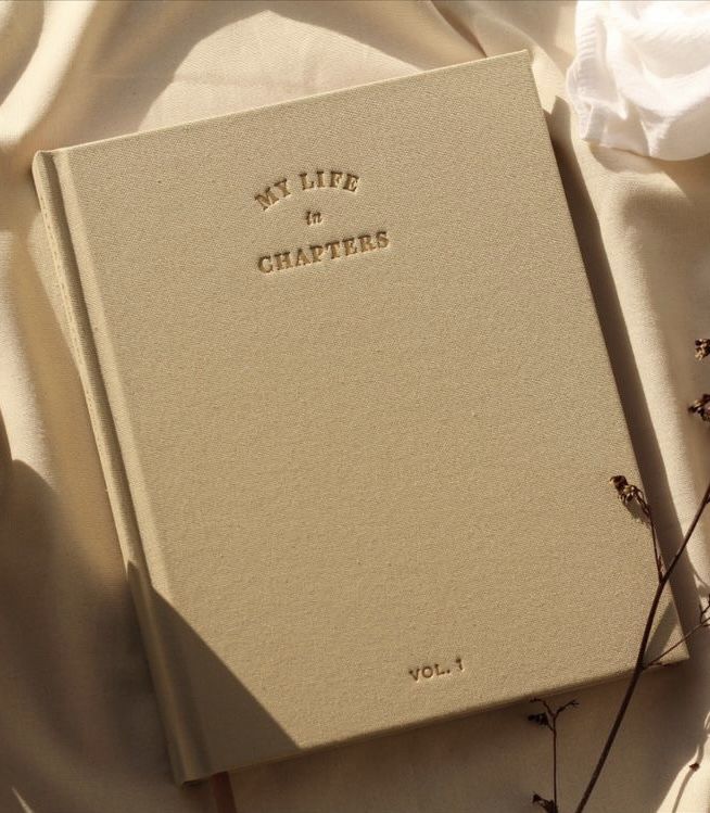 a white book sitting on top of a table next to a cup and saucer