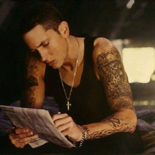 a man with tattoos is reading a paper