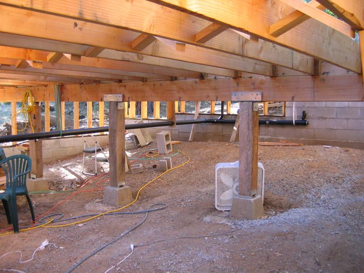 an unfinished room with two air conditioners on the floor and some chairs in the background