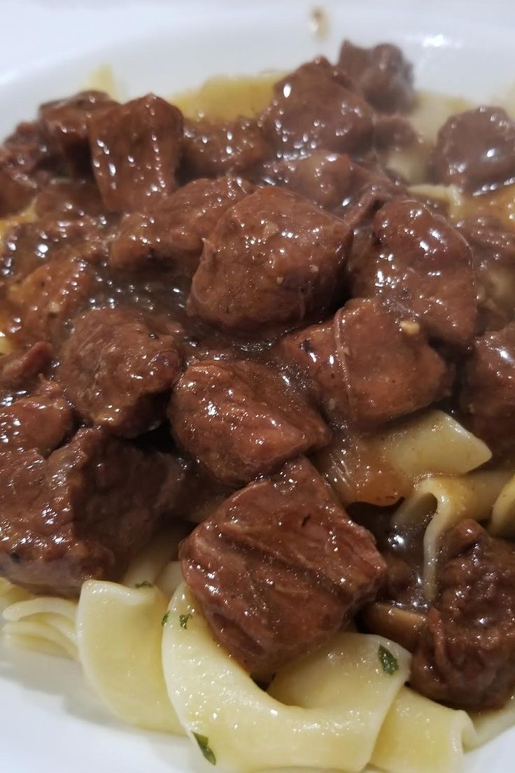 a white plate topped with meat and noodles