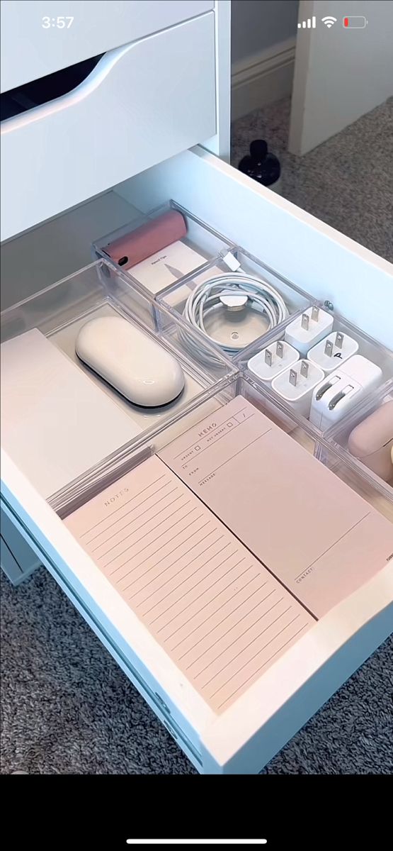 an open drawer with various items in it on carpeted floor next to white drawers