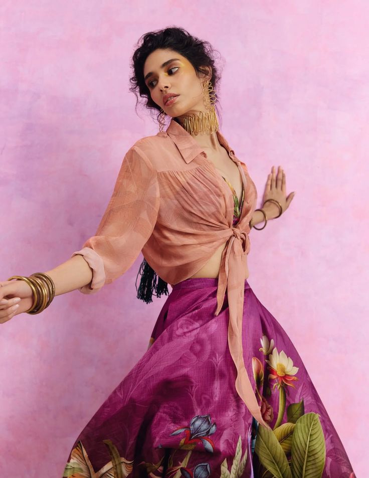 a woman in a pink dress is posing for the camera with her arms outstretched and hands out