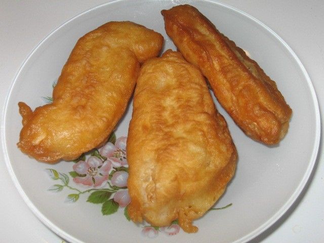 three fried fish fillets on a plate with flowers and leaves around it, ready to be eaten