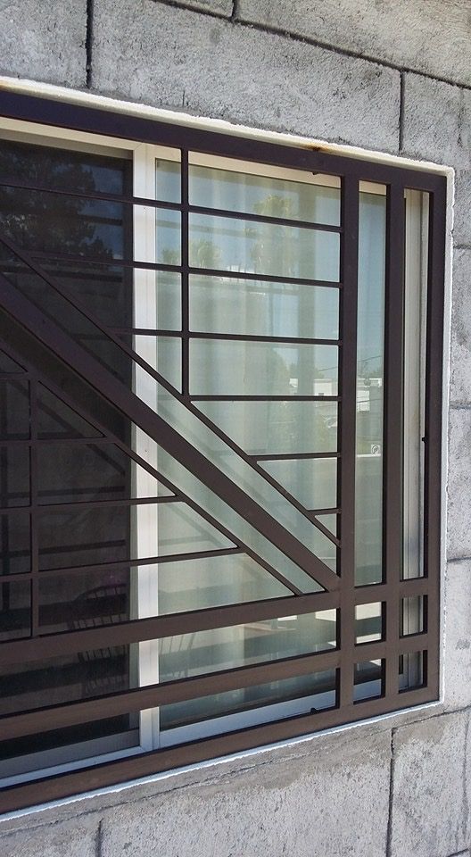 a cat sitting on top of a window sill next to a brick wall with bars