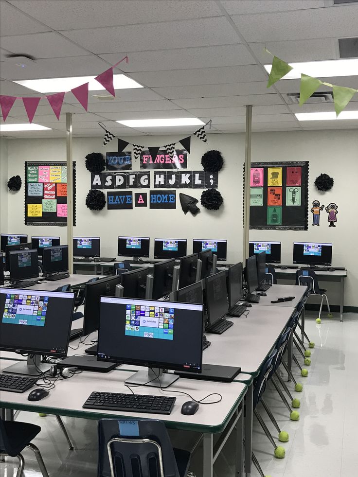 an empty computer lab with many computers on the desks and flags hanging from the ceiling