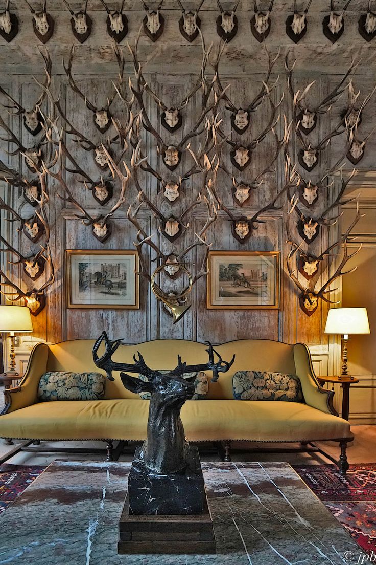 a living room with deer heads on the wall and couches in front of it