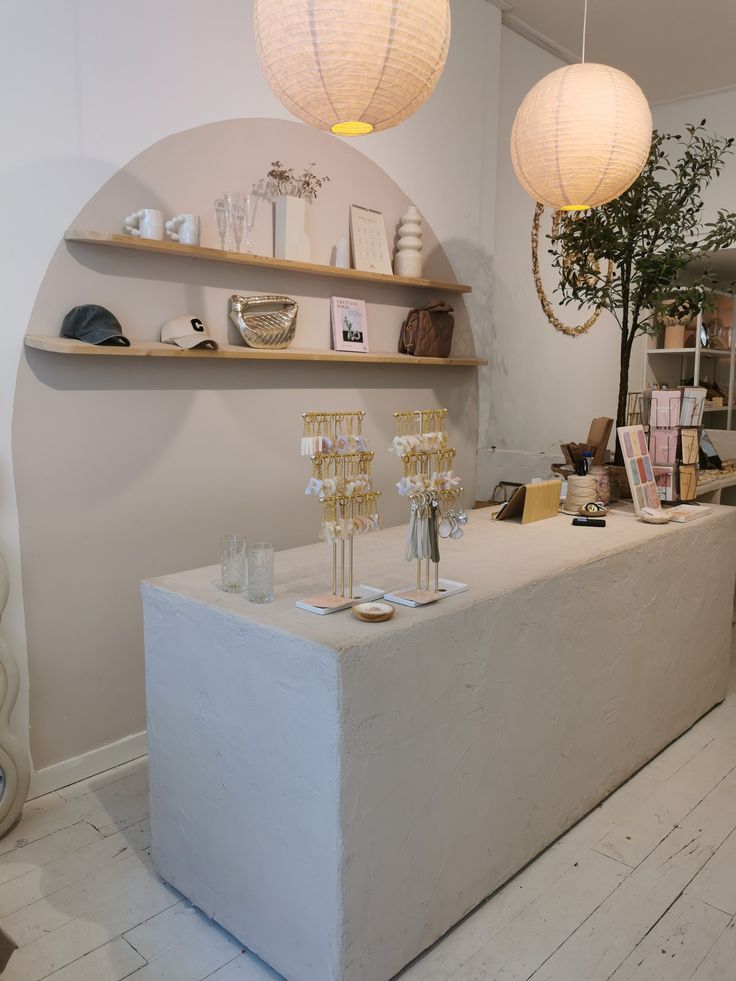 a white counter topped with lots of glasses and vases next to shelves filled with books