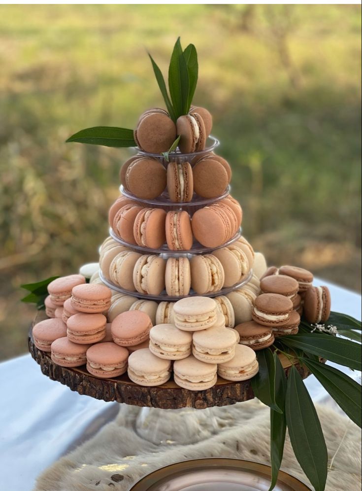 a cake made out of macaroons sitting on top of a wooden stand with leaves