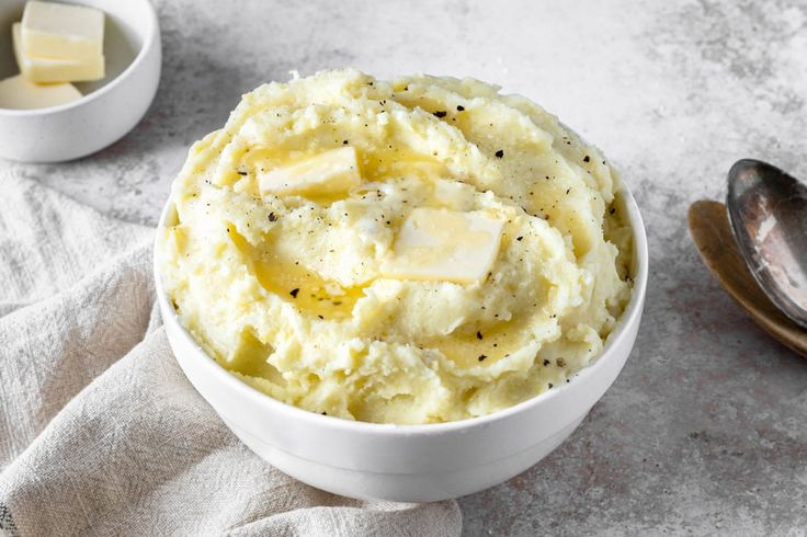 a bowl filled with mashed potatoes next to two spoons