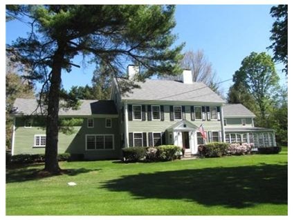 a large green house sitting in the middle of a lush green field next to trees