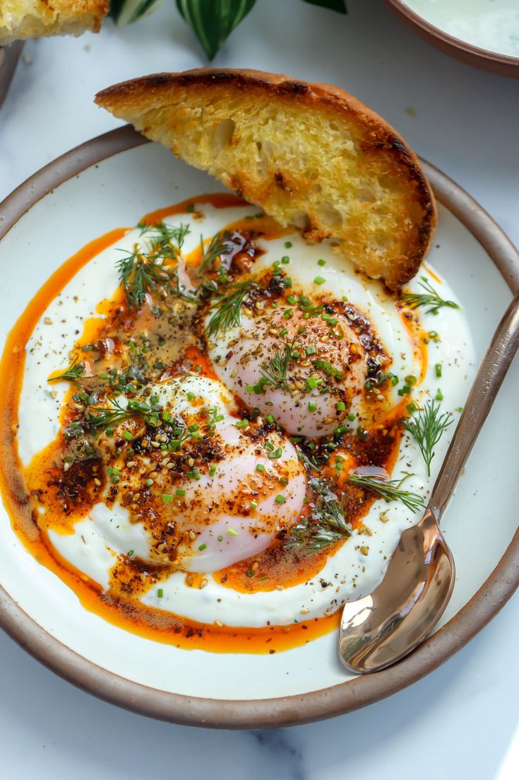 an egg dish on a plate with bread and garnished with parsley in the center