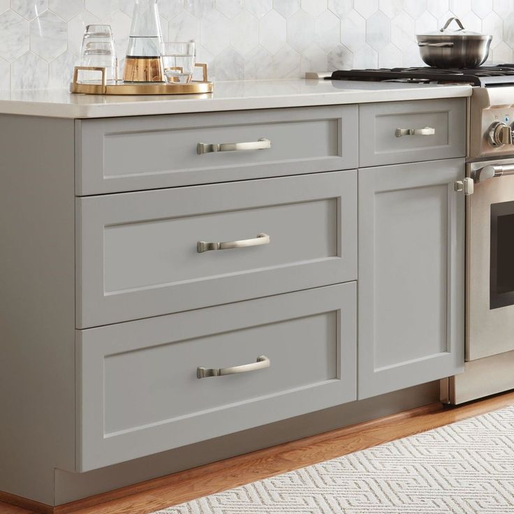 a kitchen with white cabinetry and stainless steel stove top oven in the center, along with a rug on the floor