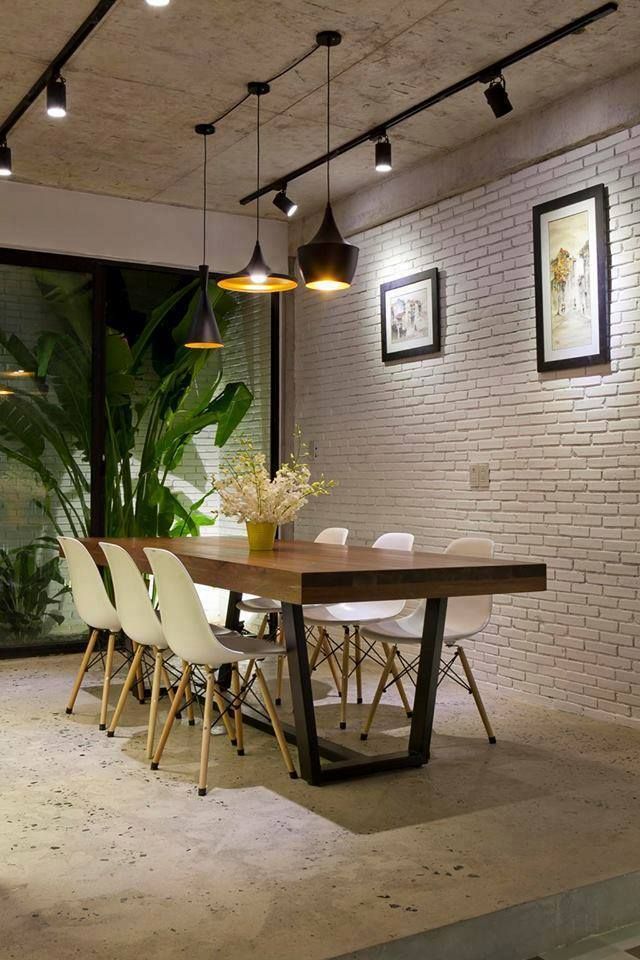 a dining room table with white chairs next to a brick wall and potted plant