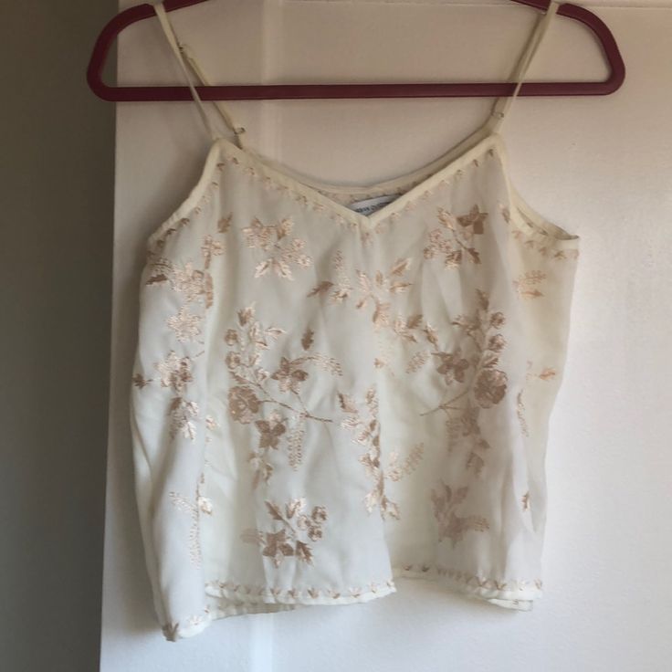 White Chiffon (?) Tank Top With Floral Embroidery Mainly On The Front But Some Details On The Bottom And Neckline! Floral Embroidered Top For Summer Wedding, Summer Floral Embroidered Top For Wedding, Embroidered Gold Tops For Summer, Gold Embroidered Summer Tops, Summer Wedding Top With Intricate Embroidery, Summer Embroidered Gold Tops, Elegant Cream Embroidered Summer Top, Elegant Embroidered Cream Top For Summer, Gold Tops With Floral Embroidery For Party