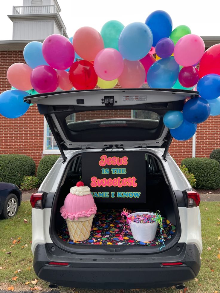 the back of a car with balloons and ice cream in it's trunk that is filled with confetti