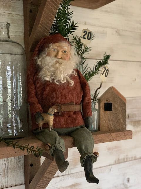 a santa clause doll sitting on top of a shelf next to a birdhouse and glass jar