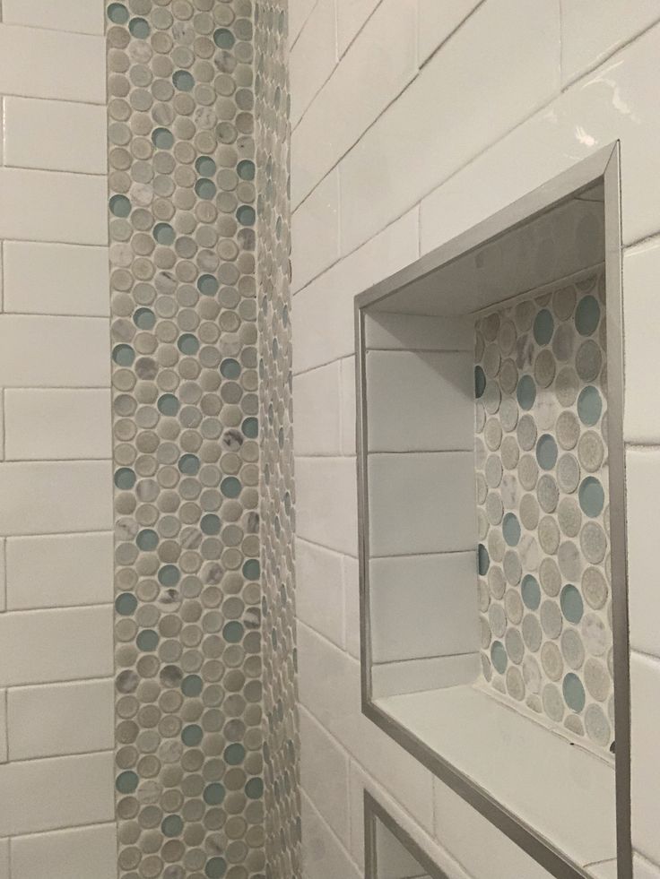 a bathroom with white tile and blue circles on the shower wall next to the toilet