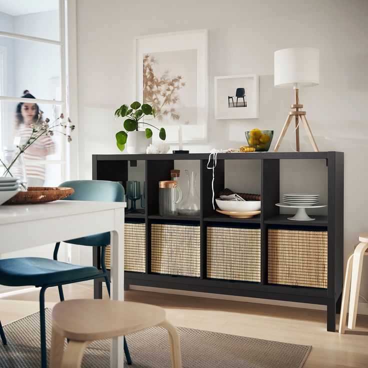 a dining room table and chairs with baskets on the bottom shelf in front of it