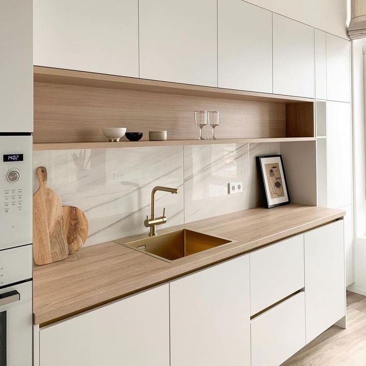 a kitchen with white cabinets and wooden counter tops, including a gold faucet