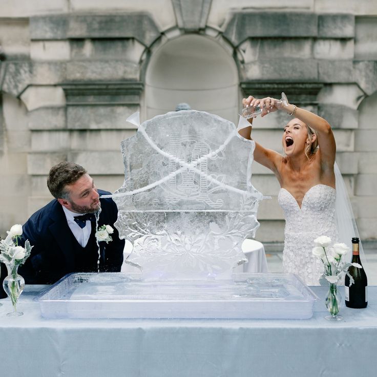 a bride and groom sitting at a table with an ice sculpture