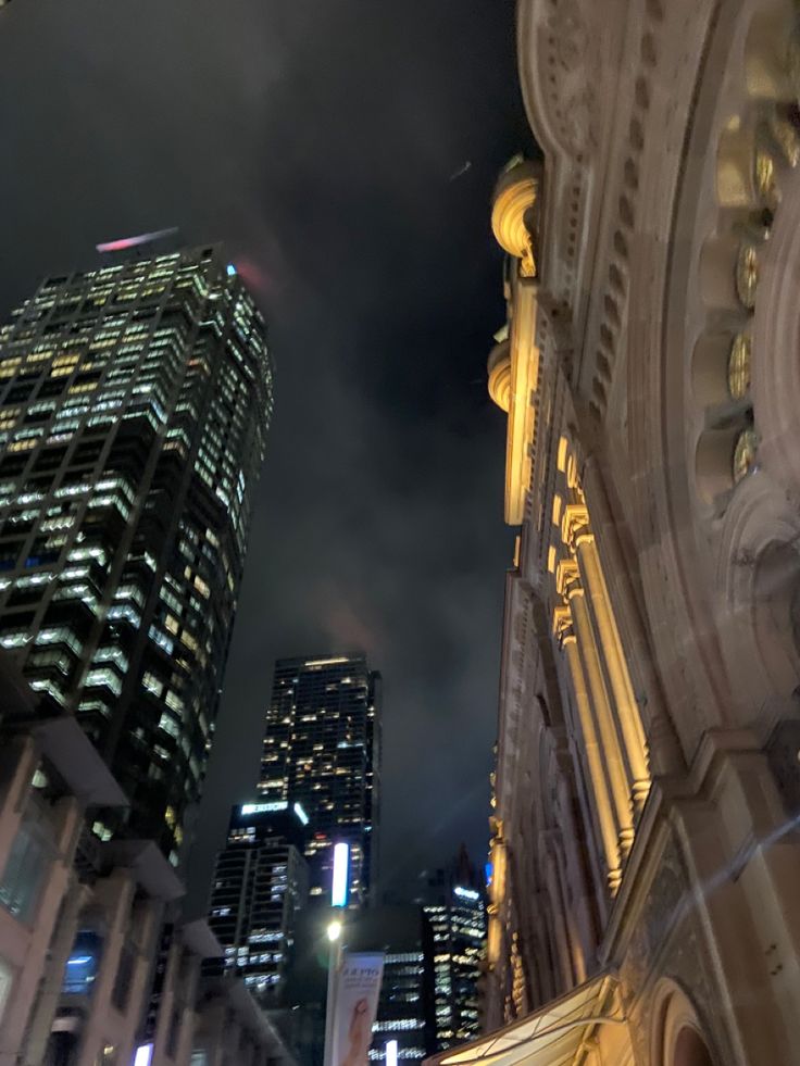 the city skyline is lit up at night with skyscrapers in the foreground and clouds in the background