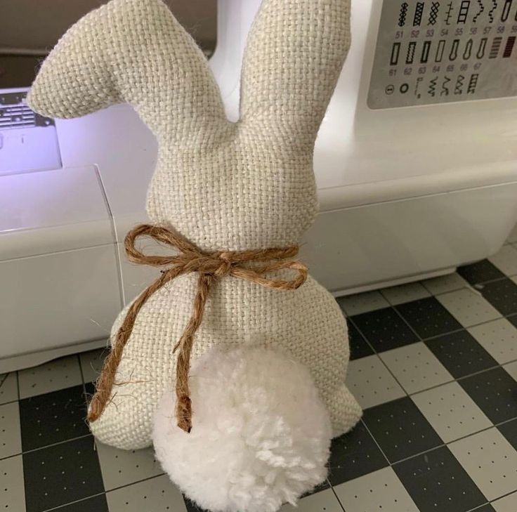 a stuffed rabbit sitting on top of a tiled floor next to a sewing machine in a room