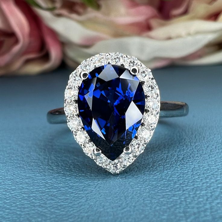 a blue and white diamond ring sitting on top of a table