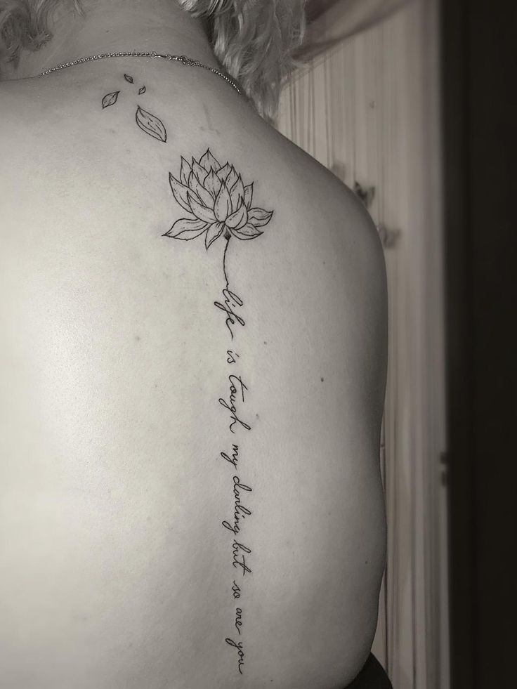 the back of a woman's shoulder with a lotus tattoo on it