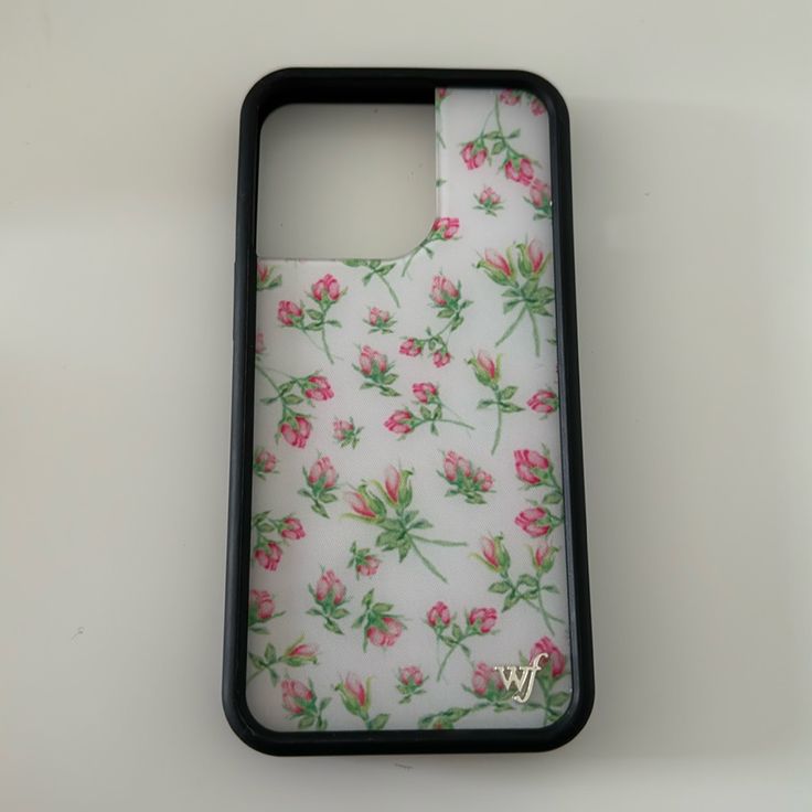 a phone case with pink flowers on white fabric and black frame, sitting on a table