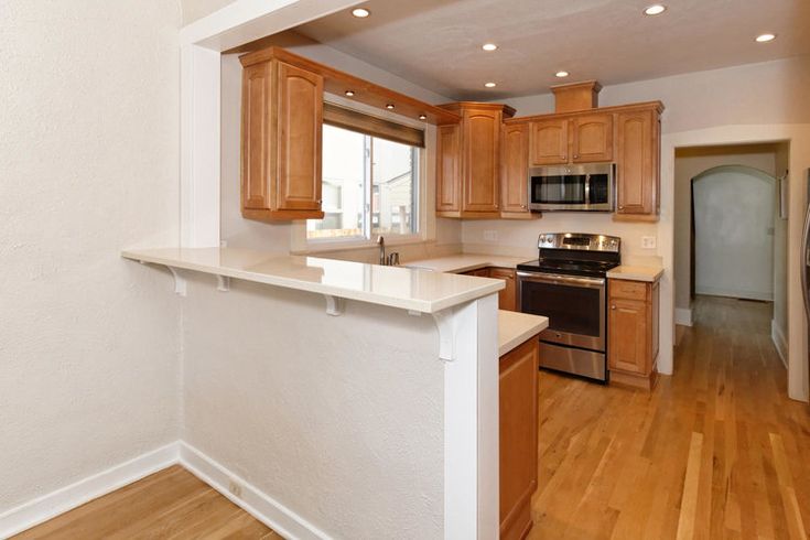 an empty kitchen with wood floors and white walls