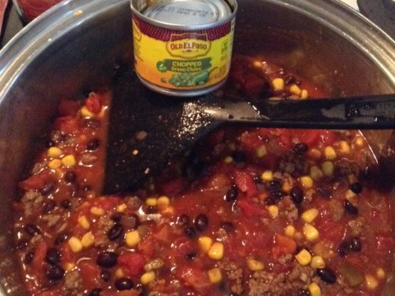 a pot filled with chili and corn next to a can of canned food on top of a stove