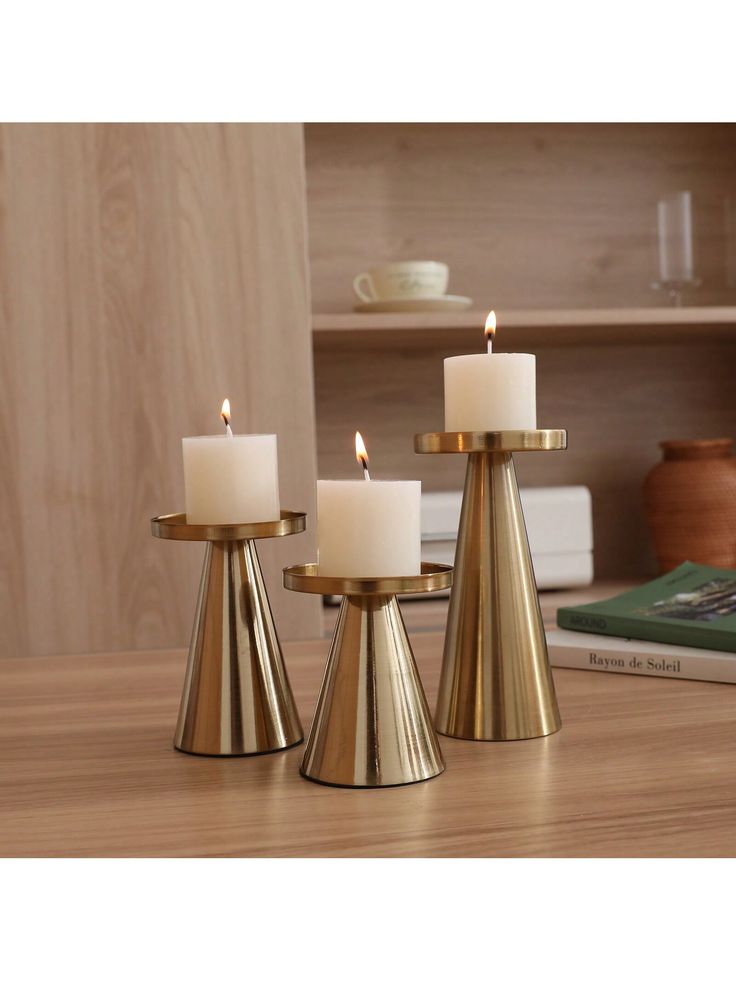 three brass candlesticks on a wooden table