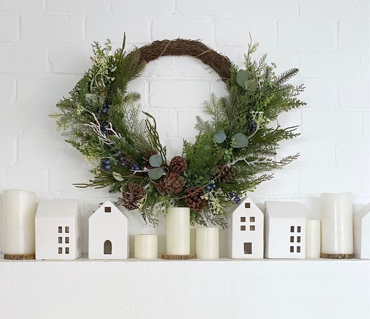 a wreath on top of a mantle next to candles