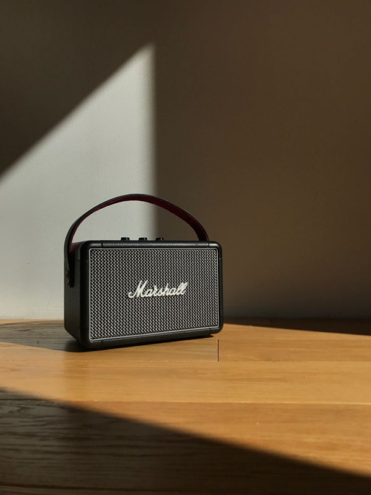 an old fashioned radio sitting on top of a wooden table next to a wall with the word marshall written on it