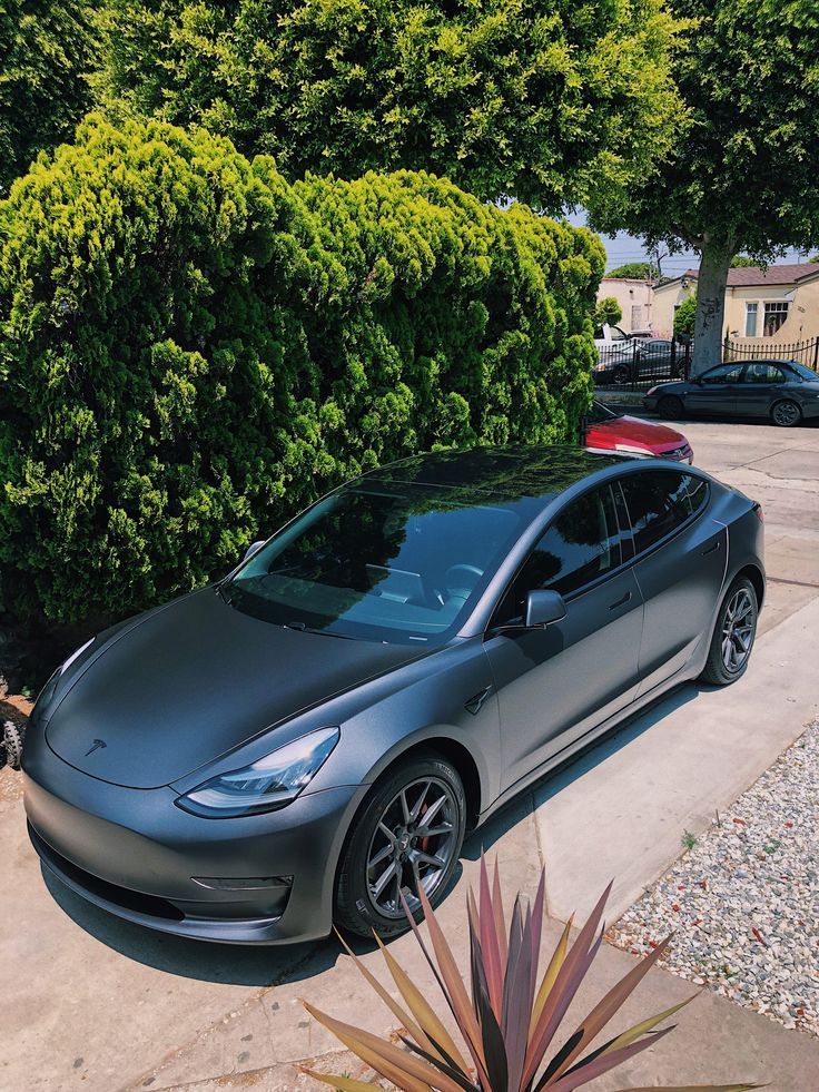 a grey car parked in front of some trees