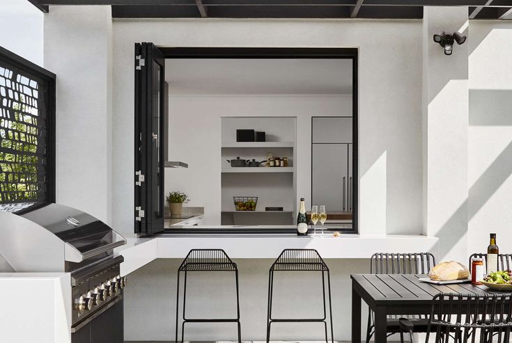 an outdoor kitchen with bar stools and table