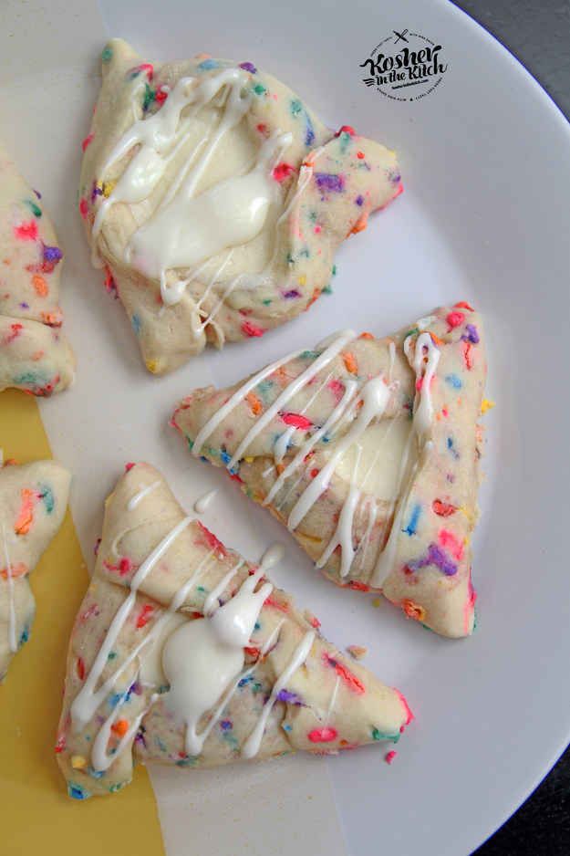 four cookies with icing and sprinkles on a plate