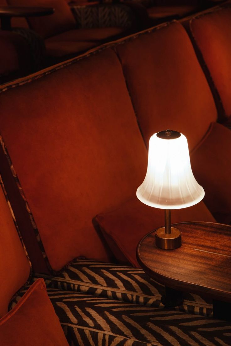 a lamp sitting on top of a wooden table next to a red couch in a room