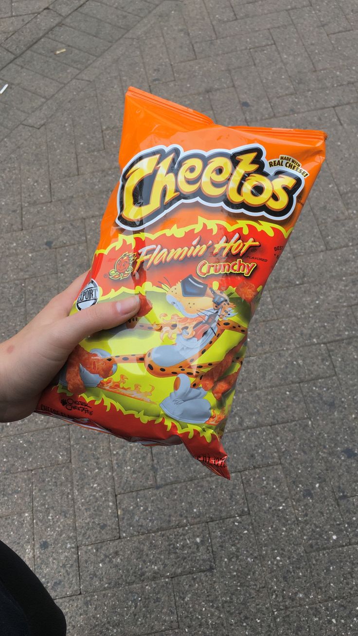 a person holding a bag of cheetos on the street