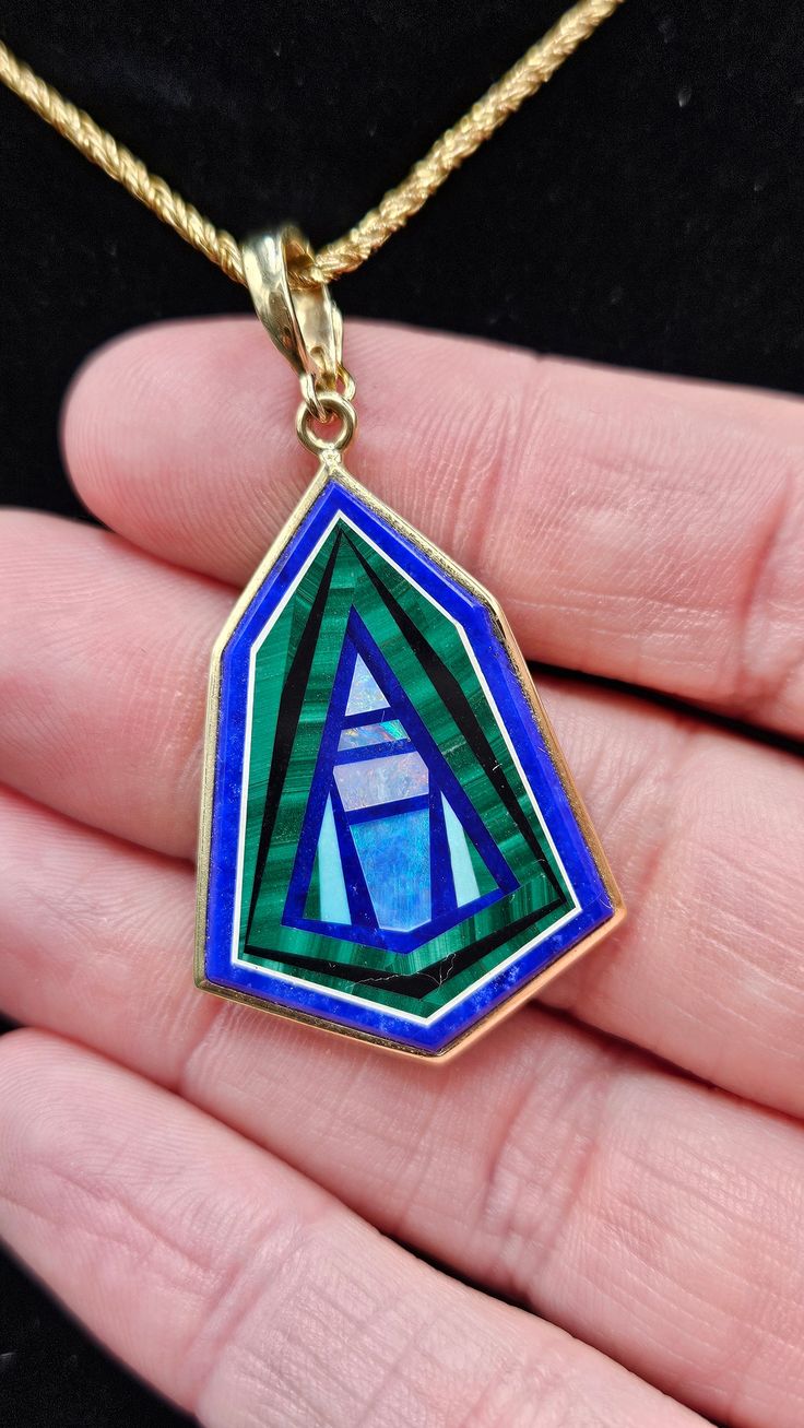 14k Intarsia set in Lapis with an enhancer bail to fit larger chains or beads. Beautiful stone inlay pendant. Intarsia is an incredible artform and this is a fantastic example. The lapis is inlayed with geometric pieces of opal, malachite, turquois, and onyx. It is bezel set in 14k with an open back exposing the lapis base. No two are alike so each one is unique. Literally wearable art. I love wearing this one on an omega, a strand of turquois beads, or a thicker gold chain.  Enhancer bail stamp Modernist Blue Gemstone Jewelry, Art Deco Cabochon Pendant Jewelry, Art Deco Sterling Silver Cabochon Jewelry, Art Deco Multi-stone Collectible Jewelry, Modernist Gemstone Jewelry For Gifts, 14k Gold Jewelry With Inlay As Gift, Modernist Green Jewelry For Gifts, Modernist Inlay Jewelry As Gift, Opal Large Pendant Jewelry