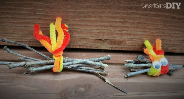 two colorful birds made out of sticks on top of a wooden table