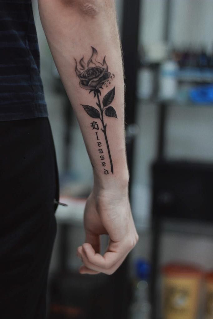 a man with a rose tattoo on his arm holding the hand of another mans wrist