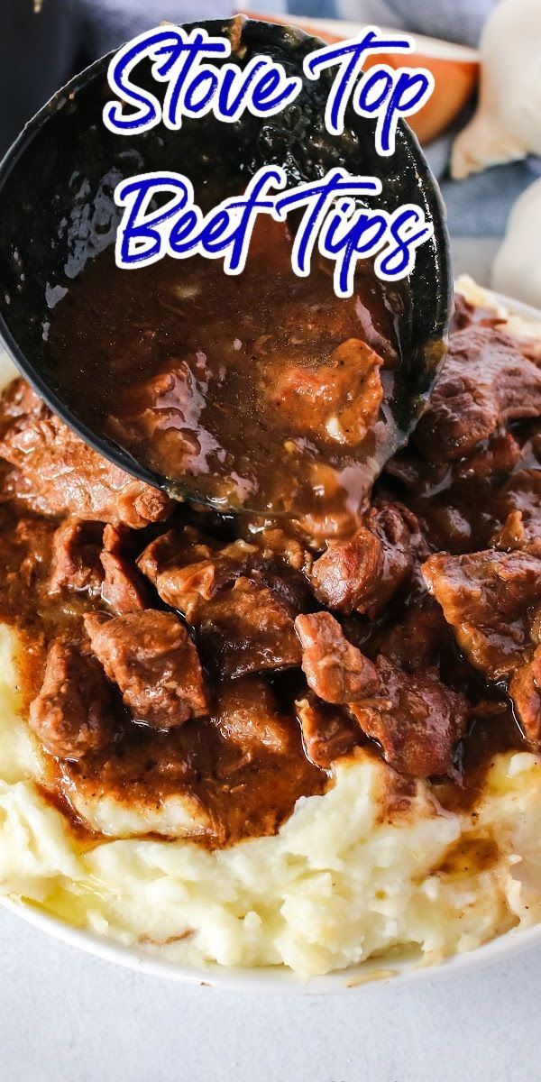 a spoon full of beef and gravy on top of mashed potatoes