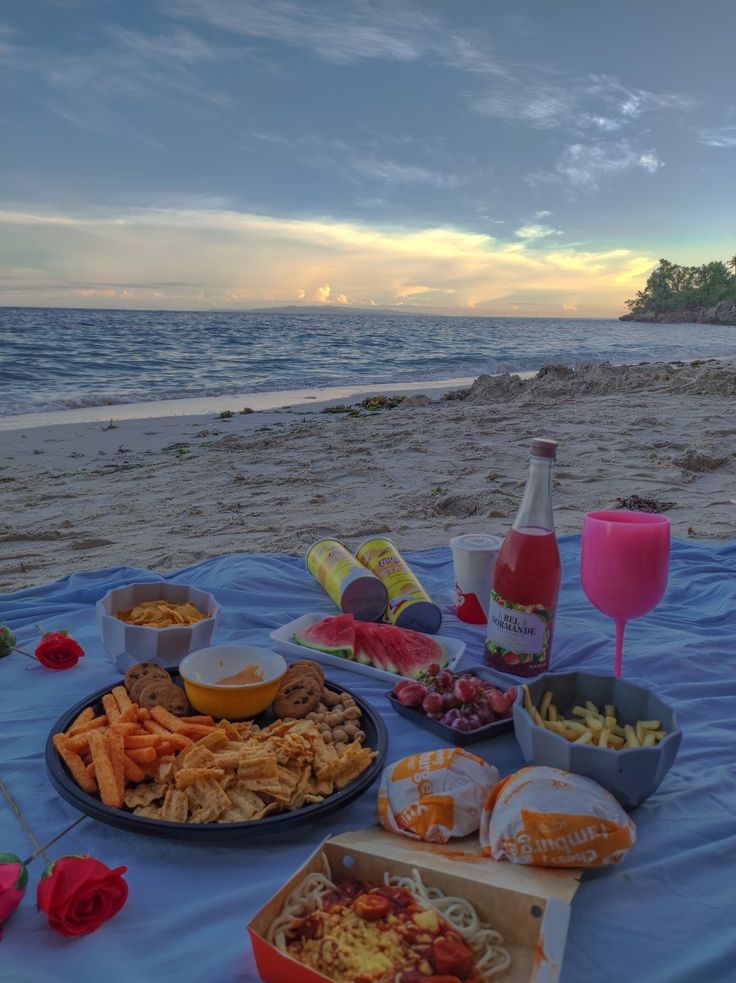 a picnic on the beach with food and drinks laid out in front of it,