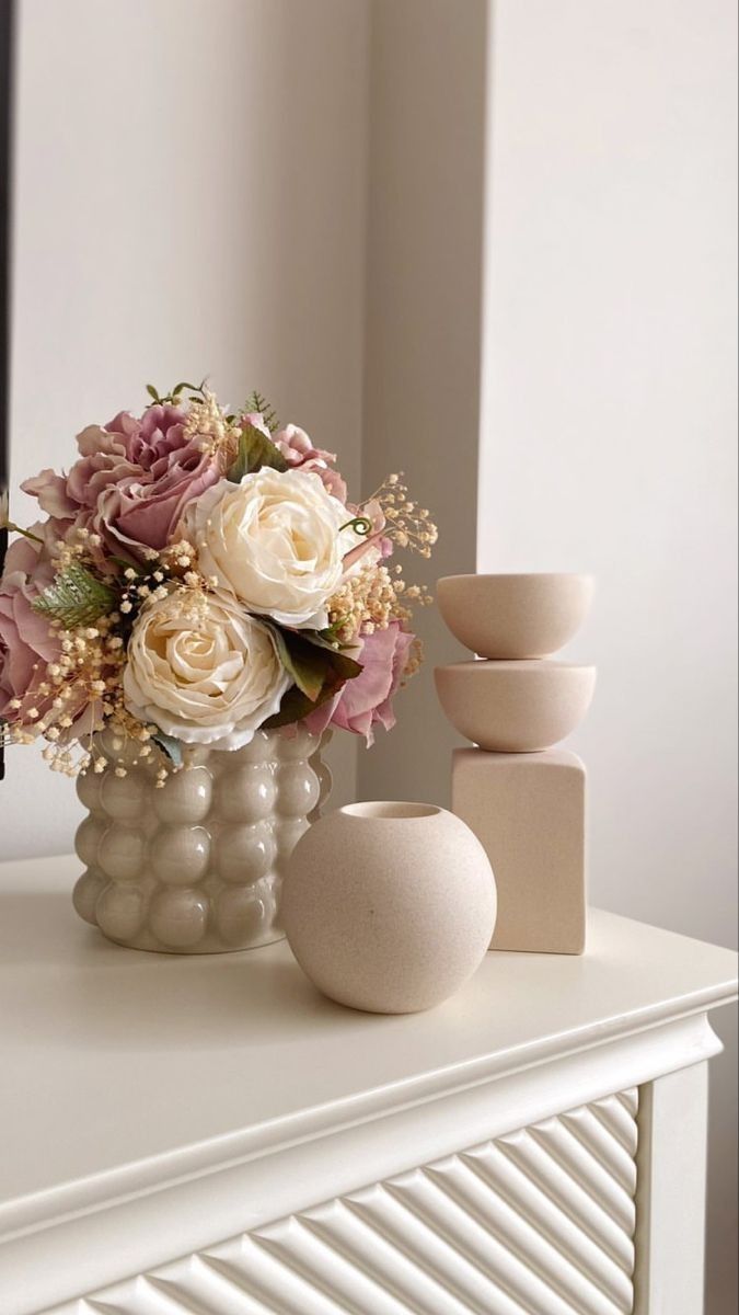 a vase filled with flowers sitting on top of a white dresser next to a mirror