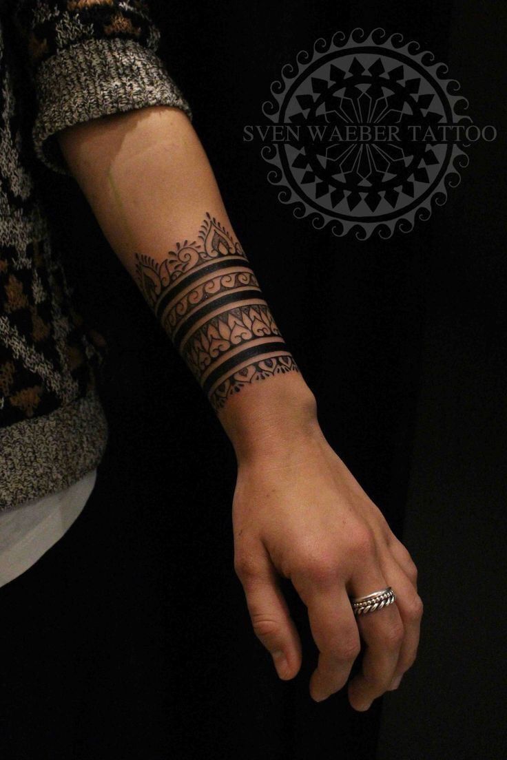 a woman's arm with tattoos on it and a ring in the middle of her hand