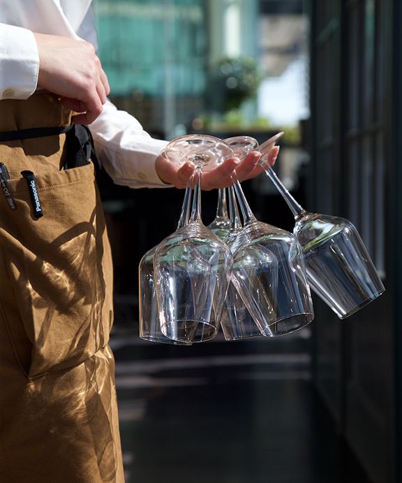 a person holding three wine glasses in their hands and hanging them from the ceiling with one hand