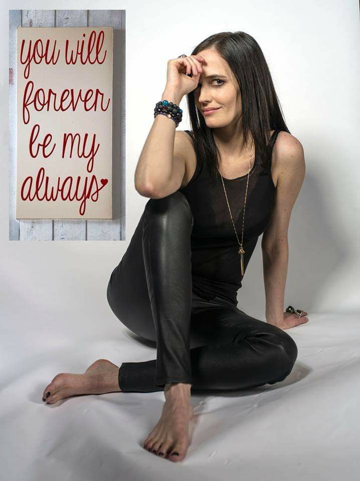 a woman sitting on the floor with her legs crossed, wearing black pants and a tank top