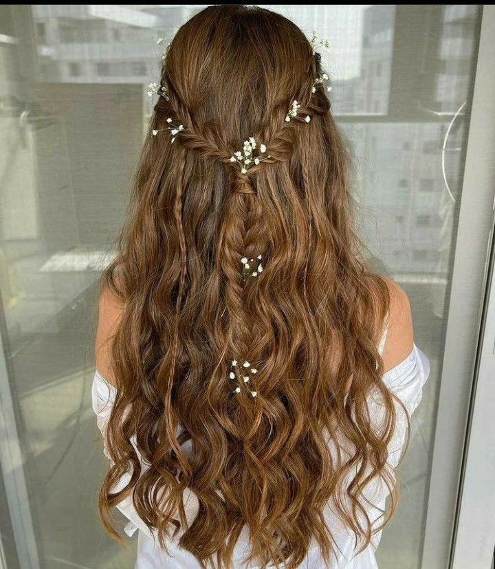 a woman with long brown hair and flowers in her hair is looking out the window