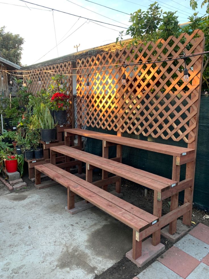 a wooden bench sitting in front of a trellis on the side of a building